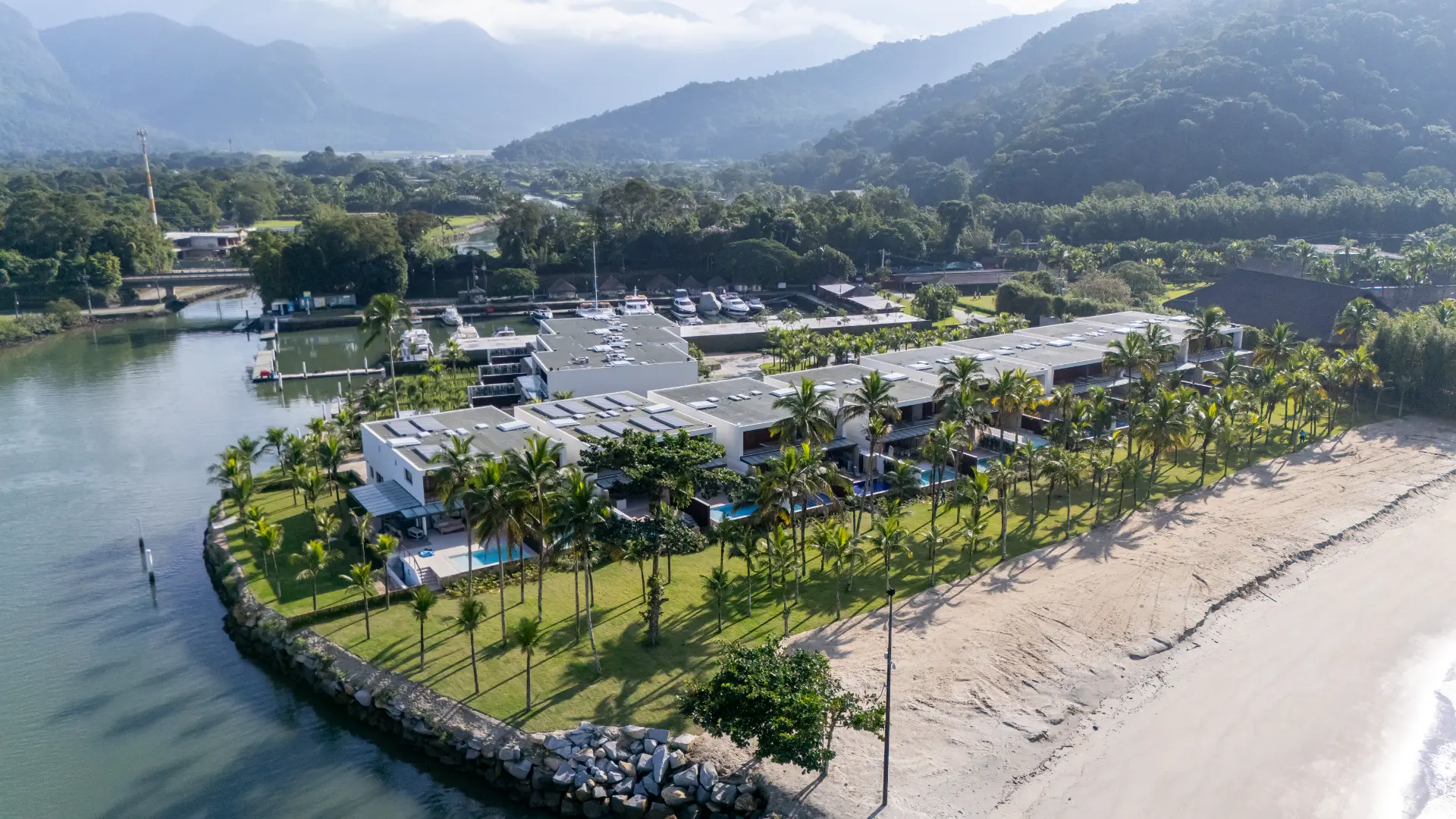 Vista aérea do Villa da Praia: casas com piscinas privativas entre a faixa de areia e o canal da Marina Portobello